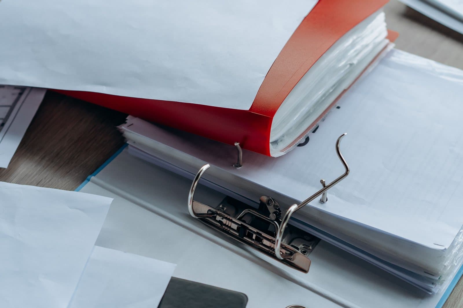 An open lever-arch file with loose pages sitting on top of it.