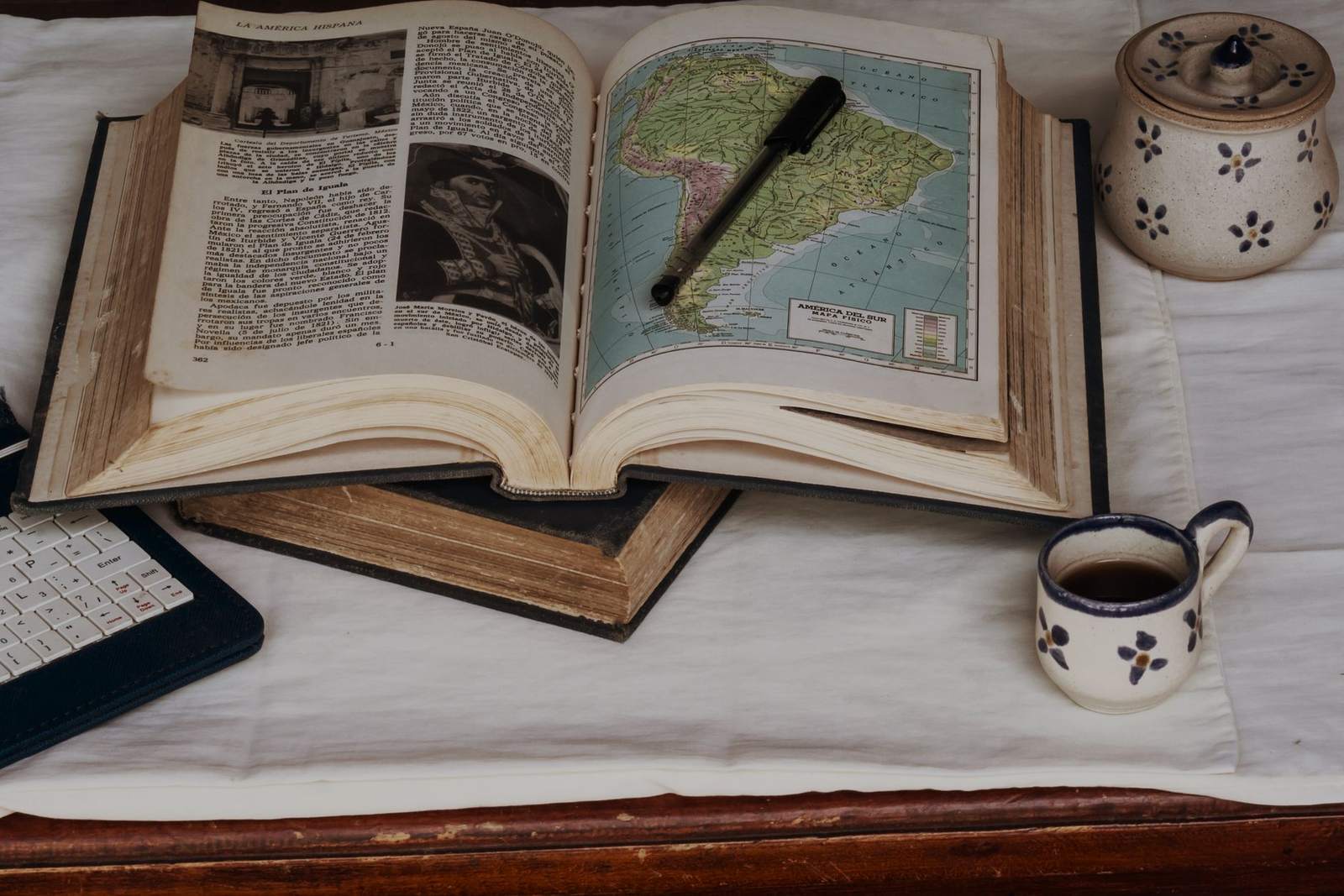 Two open reference books on a desk with a magnifying glass.