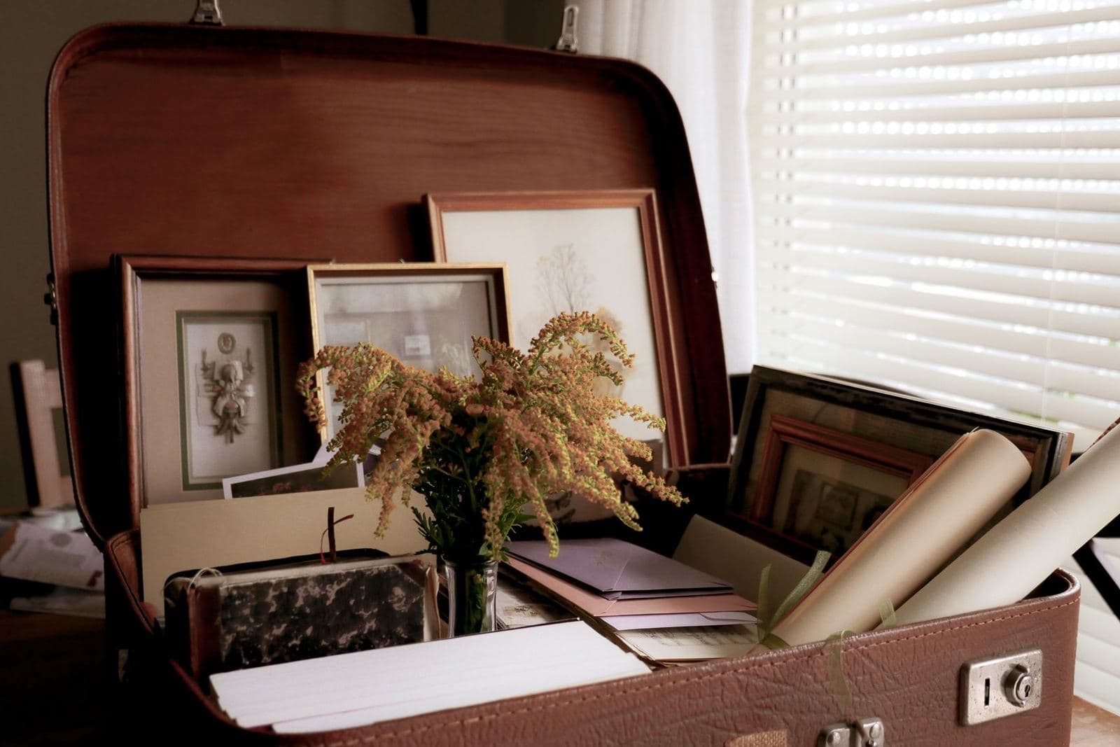 An open suitcase holding framed photographs and keepsakes.