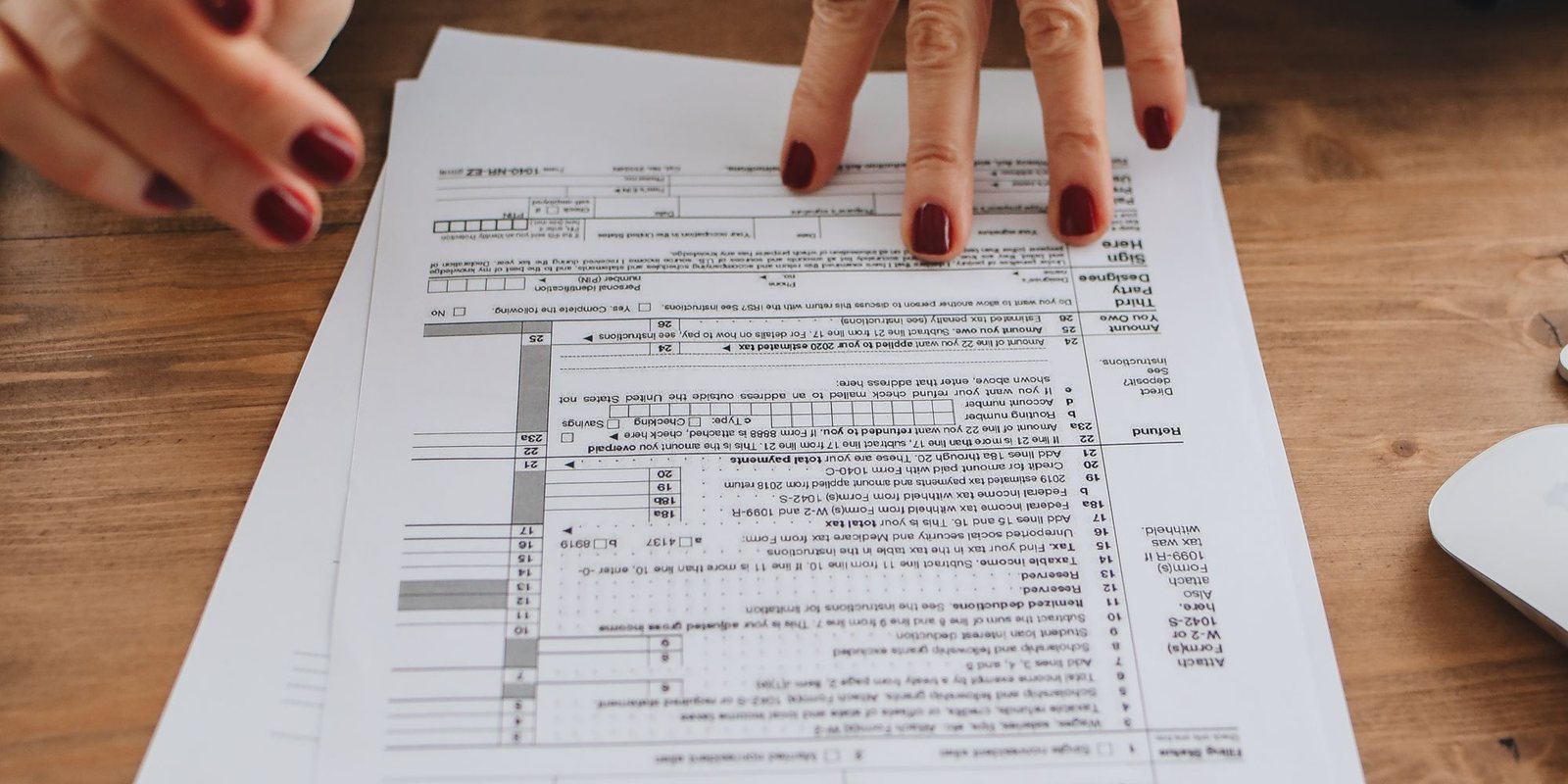 Two hands resting on a printed tax form spread across a table.