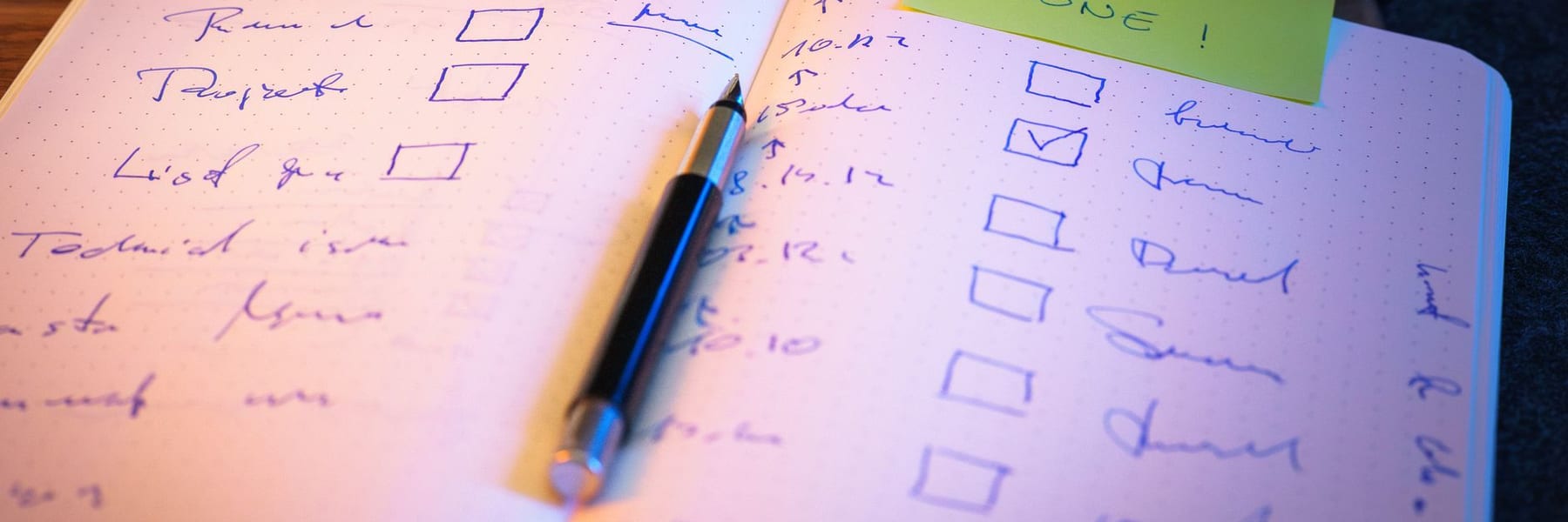 A handwritten checklist with several boxes ticked, and a pen resting on it.